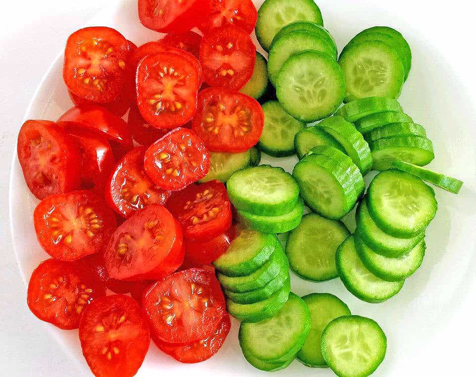 Wash and slice the tomatoes and cucumbers.