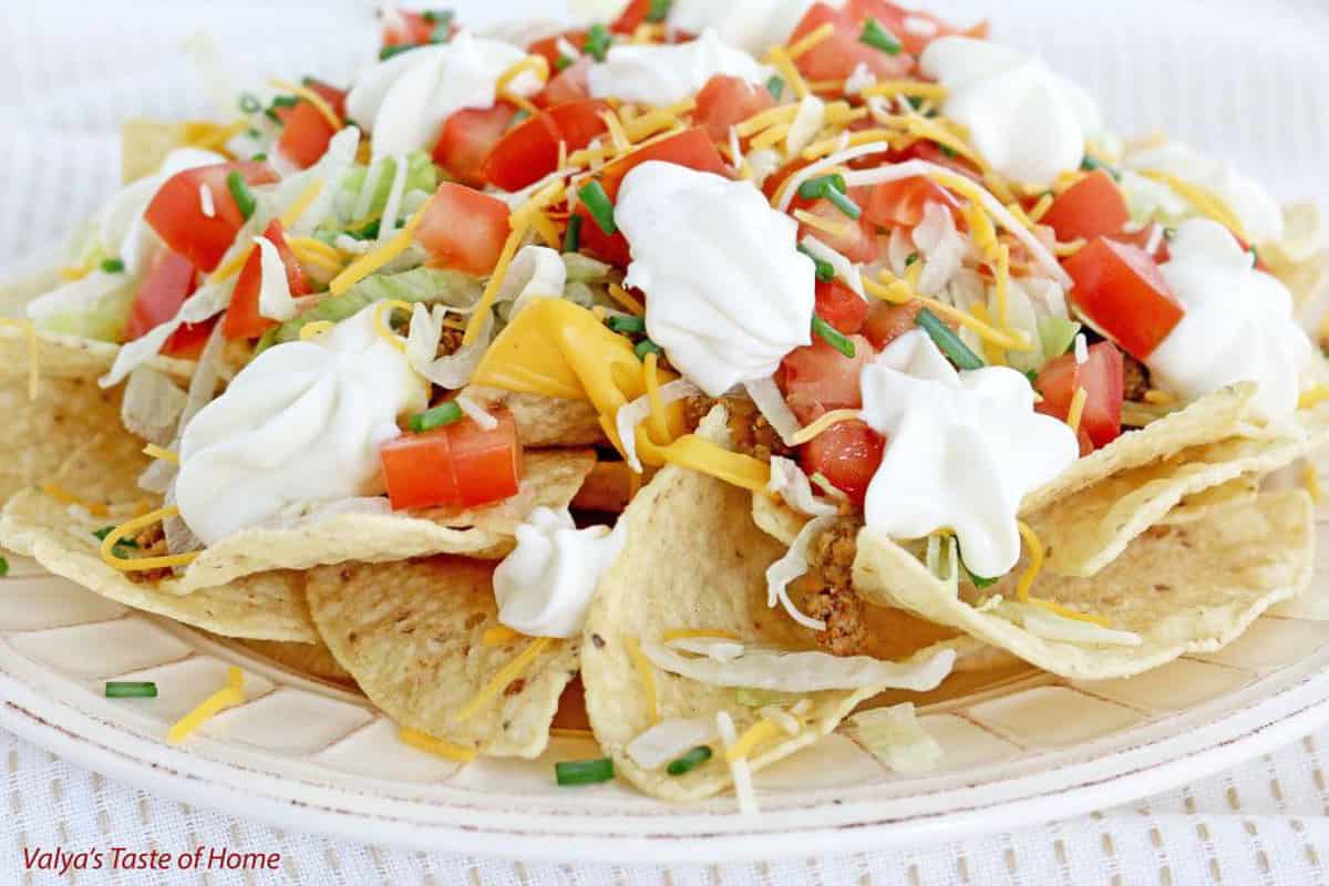 Crunchy chips with taco-flavored meat, spicy cheese, loaded with vegetables, sprinkled with extra shredded cheese, and topped off with a sour cream dressing is a tasty and easily loved meal!