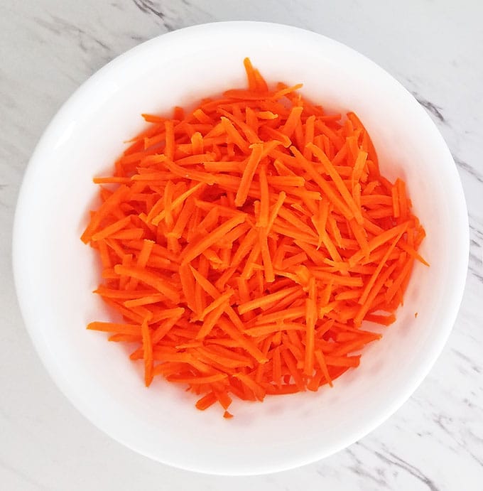 Peel, rinse, and grate carrots.