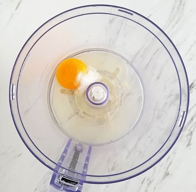 Start by adding egg (I used a cold egg instead of room temperature eggs), salt, freshly squeezed lemon juice, and garlic juice into the food processor bowl.