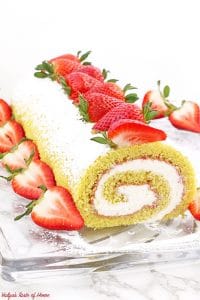 This Strawberry Vanilla Swiss Roll Recipe is the easiest and the quickest dessert you can ever make! Supper soft sponge cake topped with amazingly tasty (no cook) strawberry sauce, filled with super soft and fluffy cream, dusted with confectioners’ sugar and topped with loads of fresh strawberries.