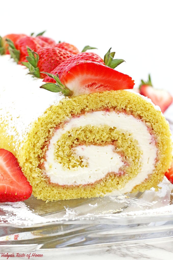 This Strawberry Vanilla Swiss Roll Recipe is the easiest and the quickest dessert you can ever make! Supper soft sponge cake topped with amazingly tasty (no cook) strawberry sauce, filled with super soft and fluffy cream, dusted with confectioners’ sugar and topped with loads of fresh strawberries.