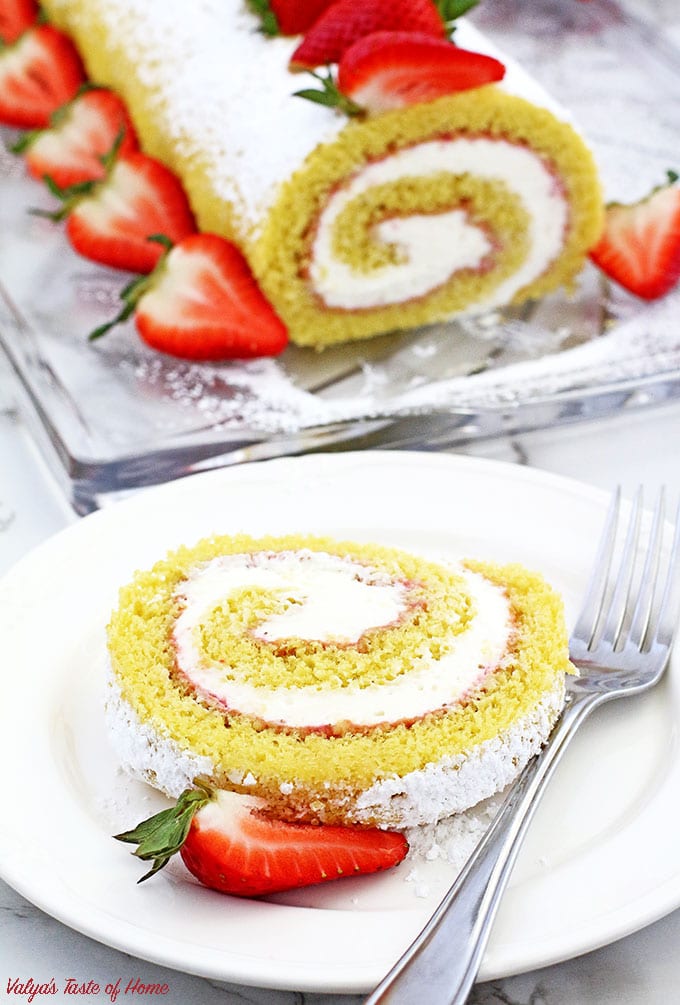 This Strawberry Vanilla Swiss Roll Recipe is the easiest and the quickest dessert you can ever make! Supper soft sponge cake topped with amazingly tasty (no cook) strawberry sauce, filled with super soft and fluffy cream, dusted with confectioners’ sugar and topped with loads of fresh strawberries. 