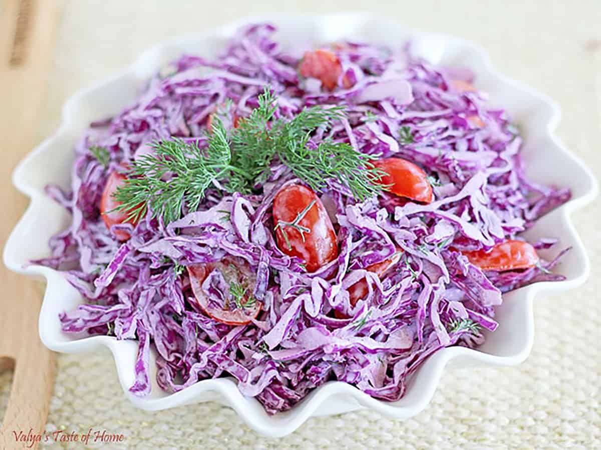 This salad is made with tender purple cabbage leaves, juicy grape or cherry tomatoes, and fresh dill as the base.