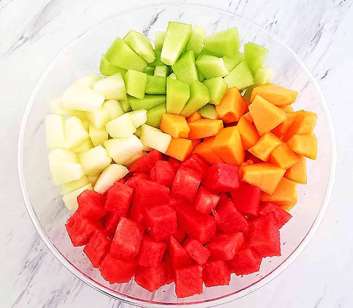 Cut all melons into cubes and place into a large bowl.