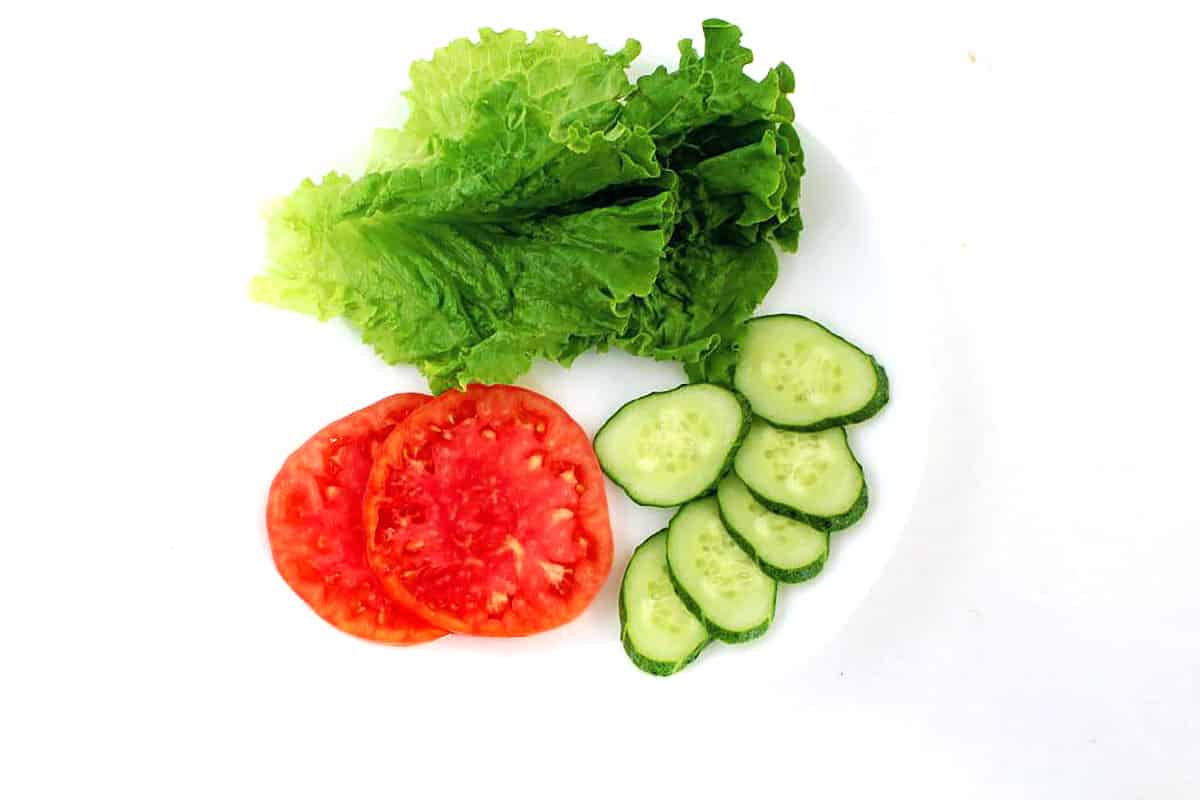 Thoroughly rinse the lettuce, tomato, and cucumber with water, then pat them dry with a paper towel. 