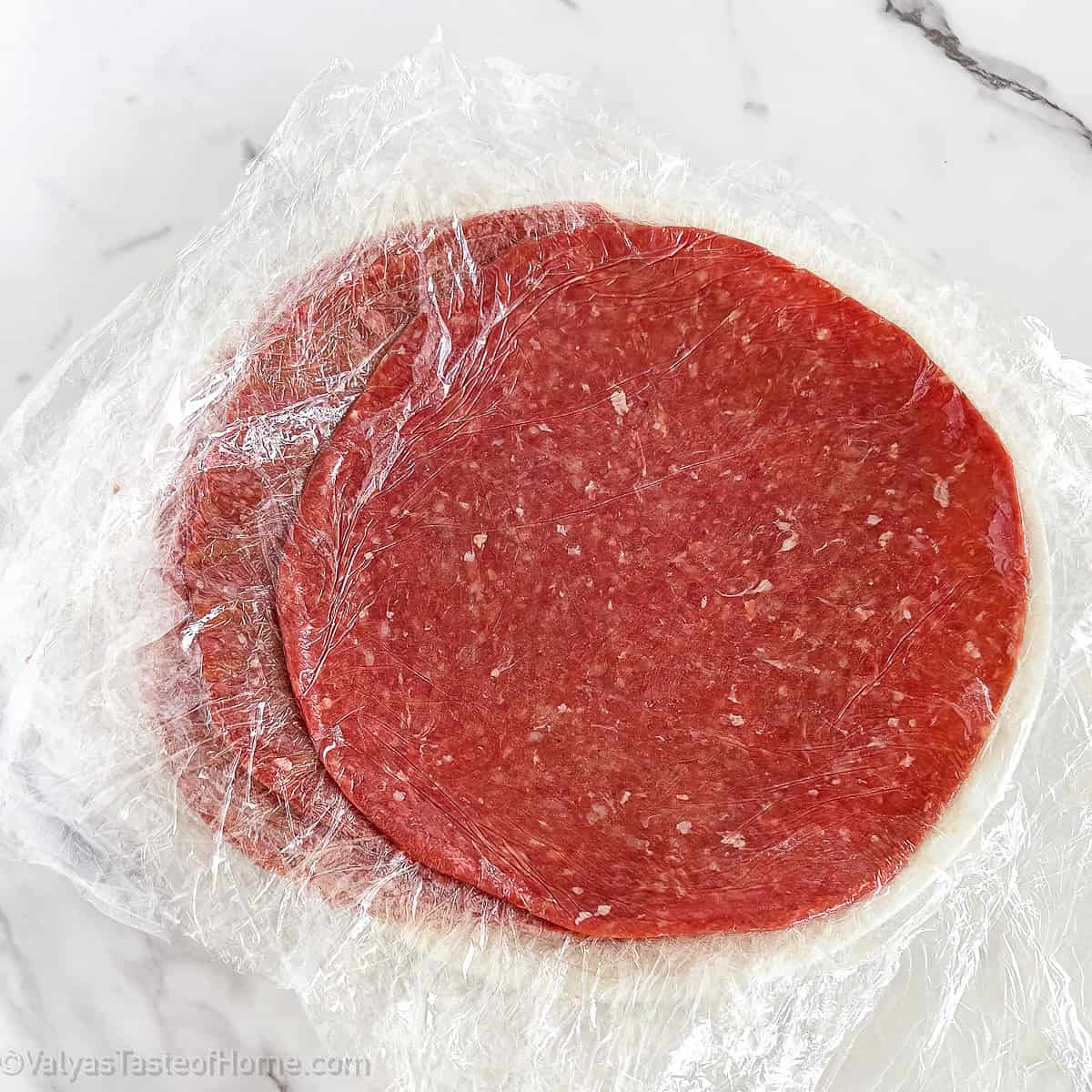 Roll one piece of ground beef at a time in between 2 layers of plastic food wrap. Make them thin and much larger than the tortilla itself.