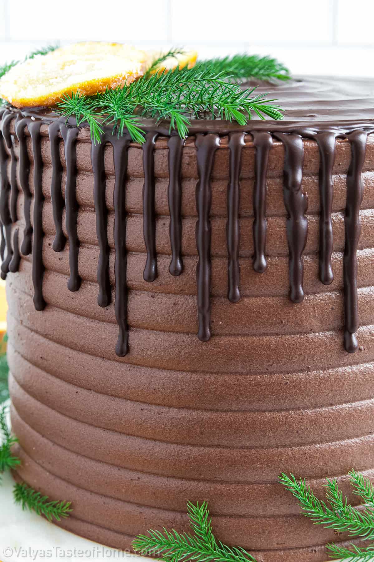 Decorate the cake with fresh pine tree stems and frosted orange slices for a festive touch. Return the cake to the fridge for a couple more hours before serving.